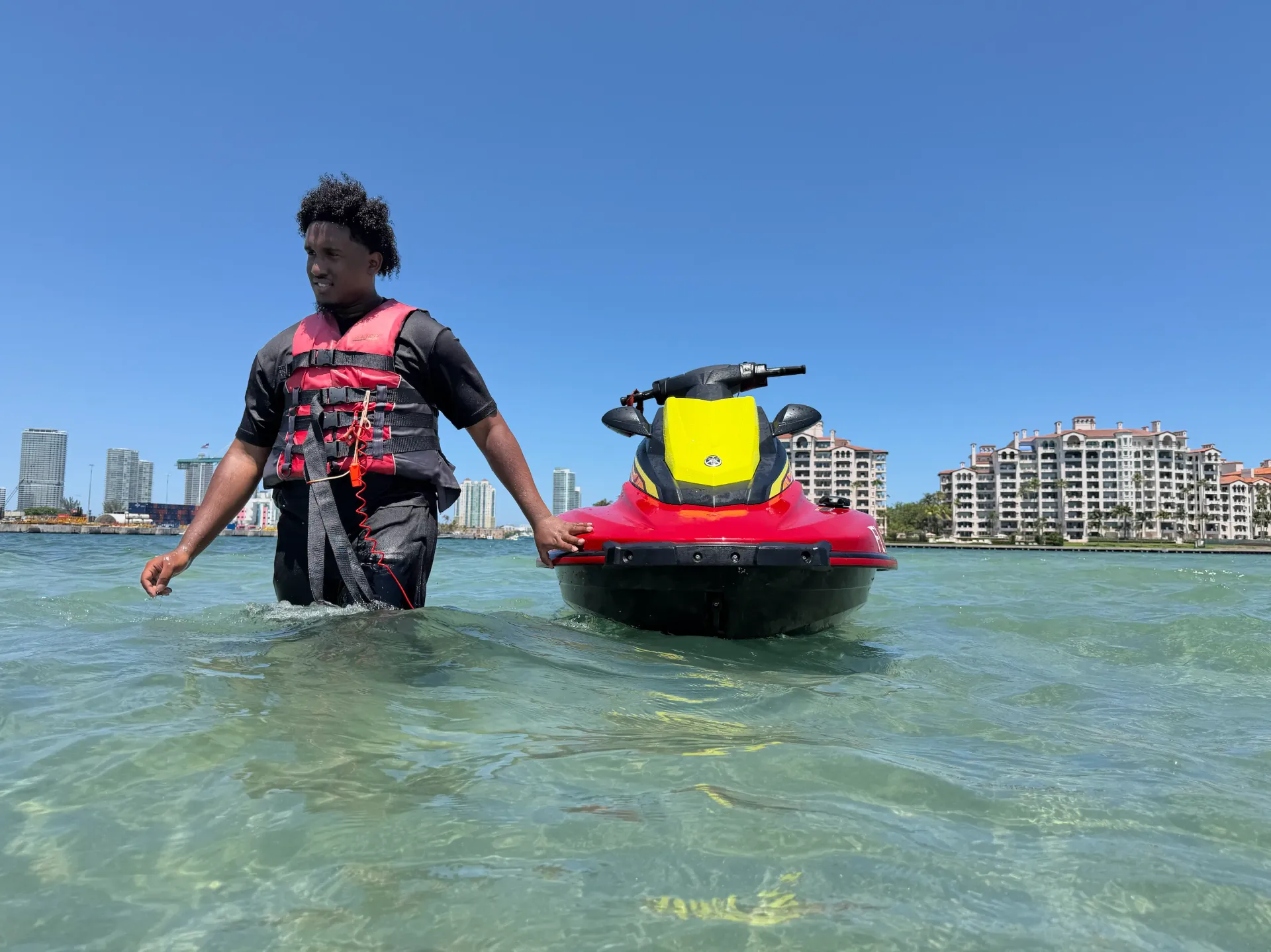 Rider standing beside a jet ski during a guided Miami Jet Ski Rentals from Bayside sandbar stop on Biscayne Bay