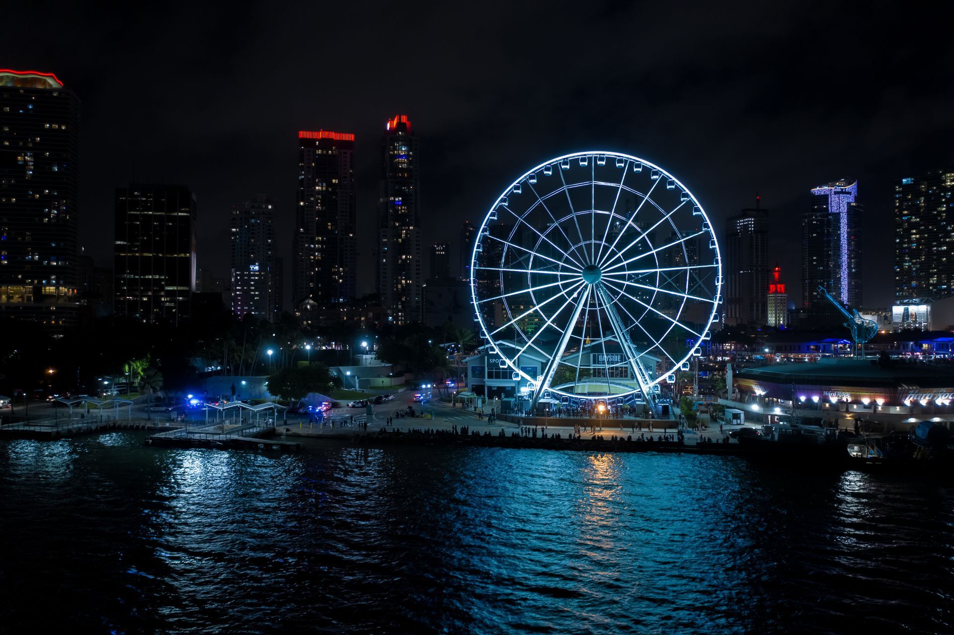 Miami Night Cruise views of the Skyviews Observation Wheel at Bayside Marketplace with illuminated Miami skyline at night.