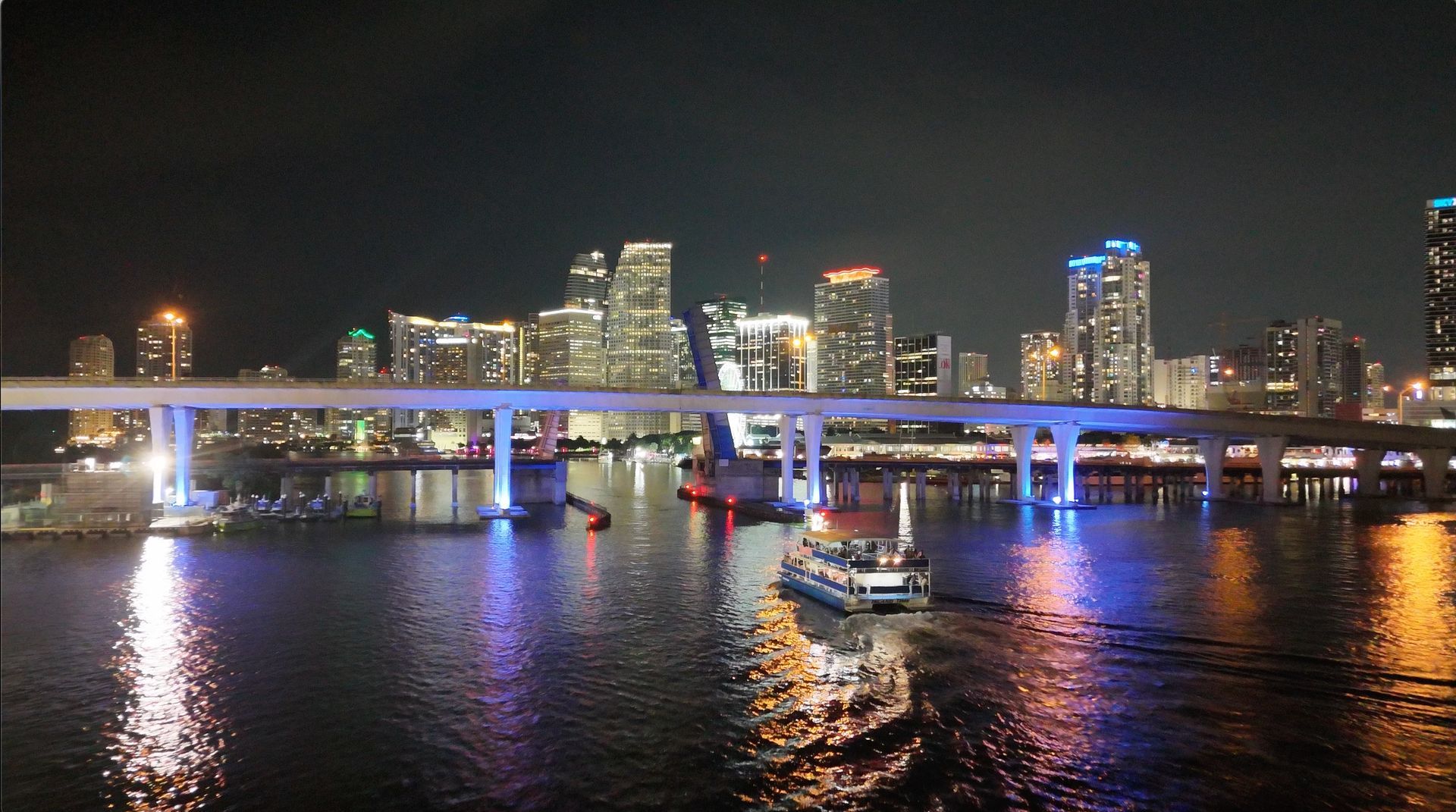 Miami skyline night views from the water with illuminated skyscrapers and reflections across Biscayne Bay.