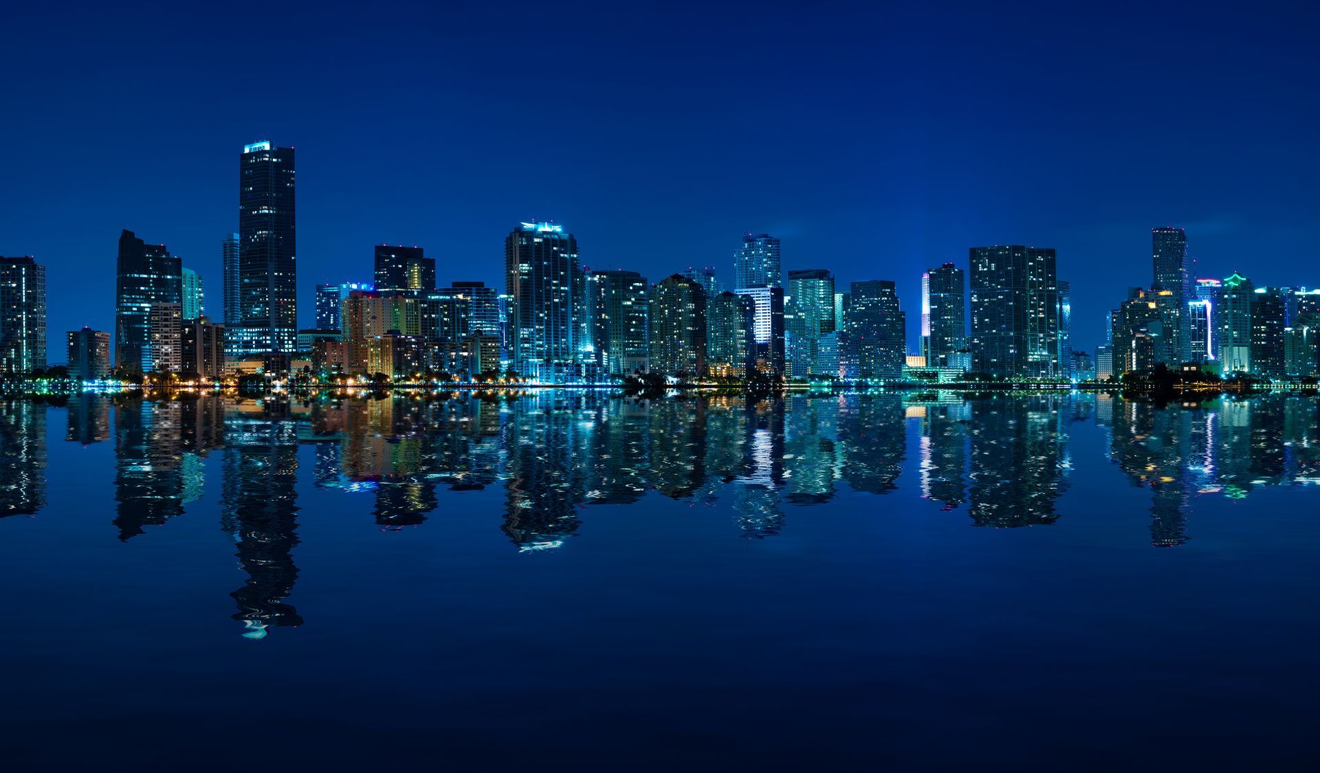 Miami Skyline Views on the waters of Biscayne Bay with illuminated downtown buildings reflected at night.