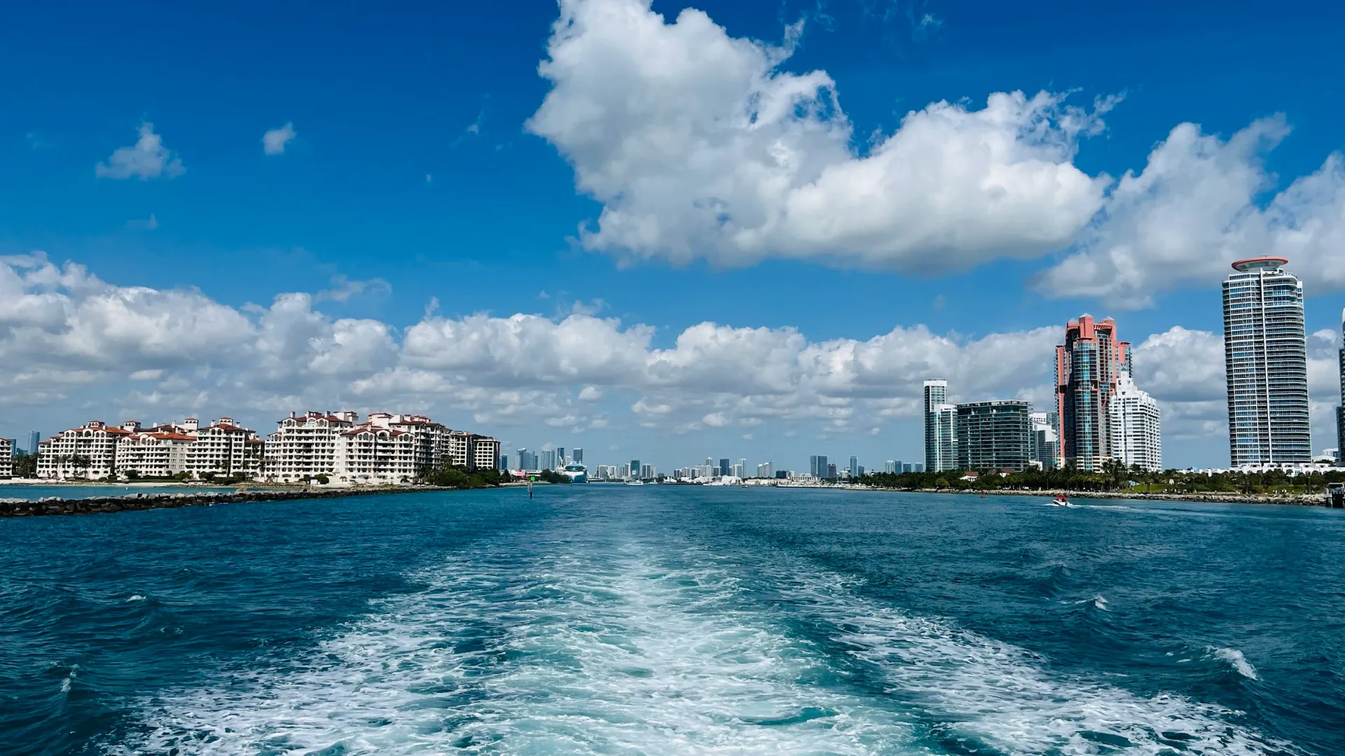 Panoramic view of the Miami waterfront from Biscayne Bay featuring Fisher Island, South of Fifth Miami Beach, PortMiami, and the Downtown Miami skyline in the distance.