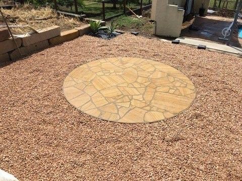 Circular Stone Patio Surrounded by Red Gravel in A Backyard — Gladstone Garden & Landscaping Supplies In Burua, QLD