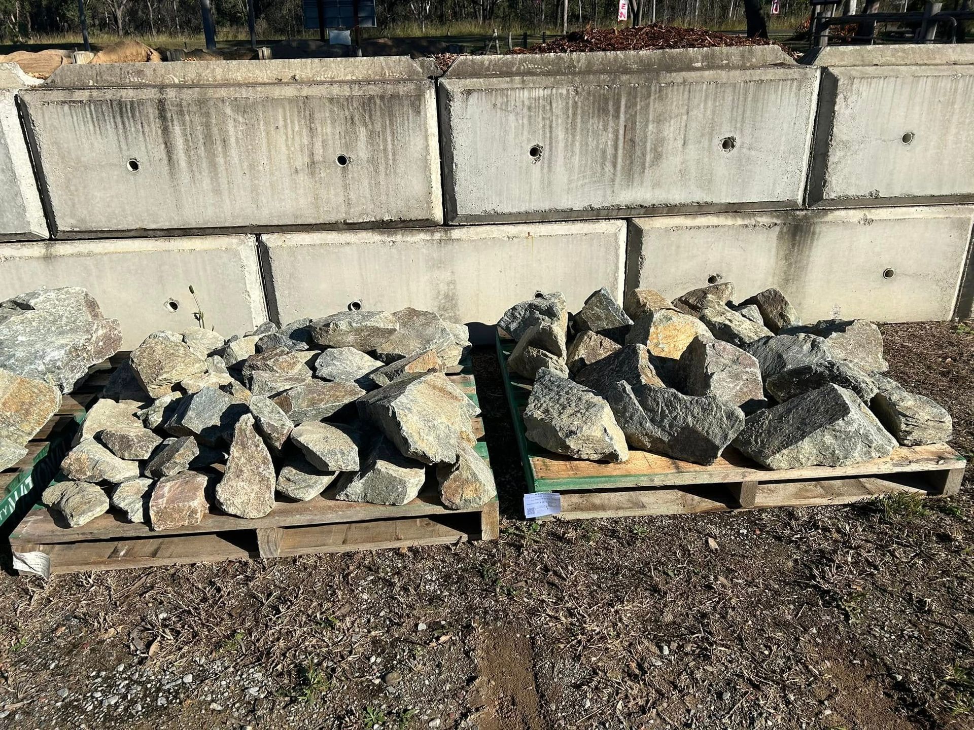 Two Pallets of Rocks in Front of Concrete Blocks — Gladstone Garden & Landscaping Supplies In Burua, QLD