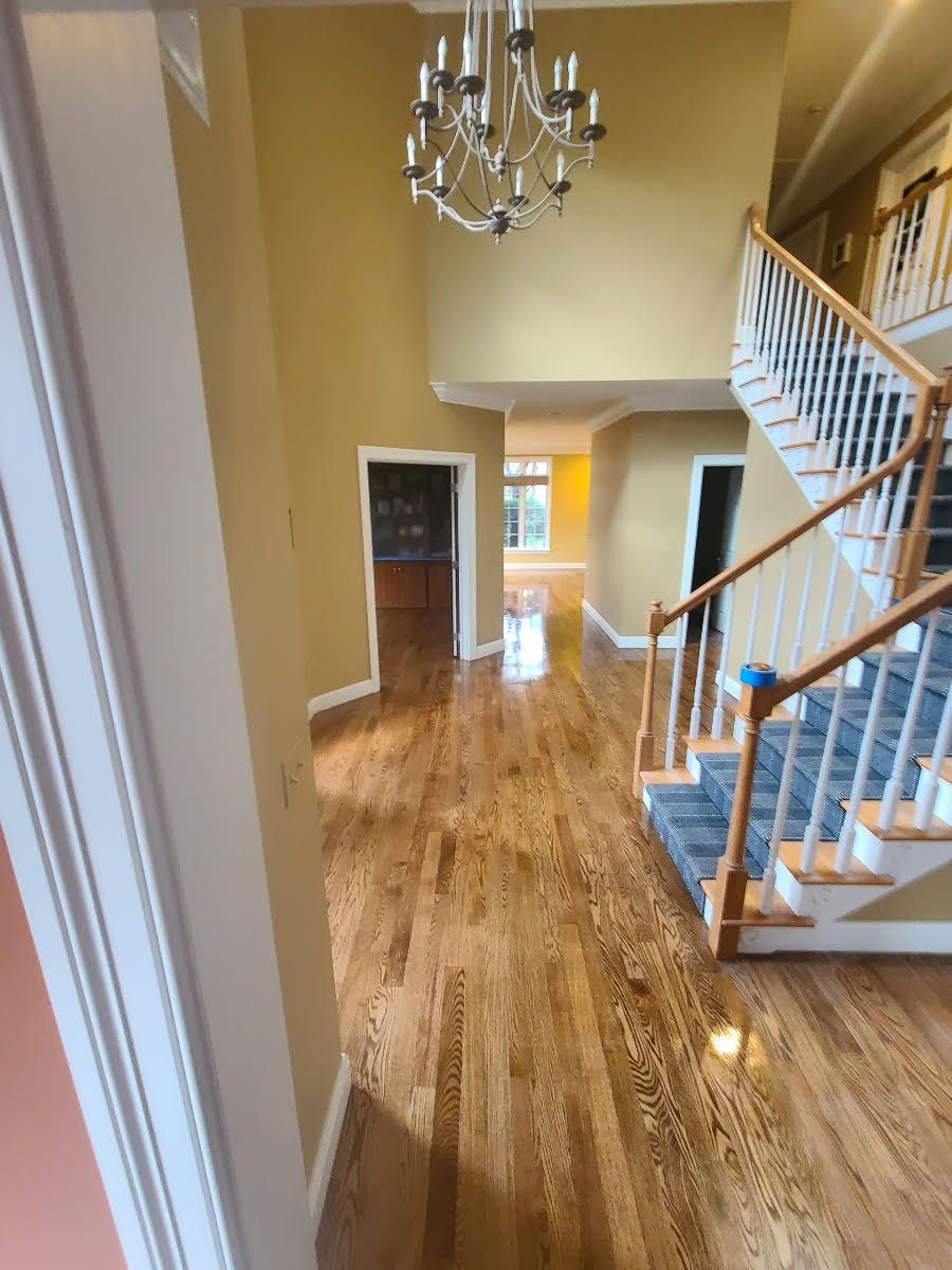 A hallway with hardwood floors and stairs in a house.