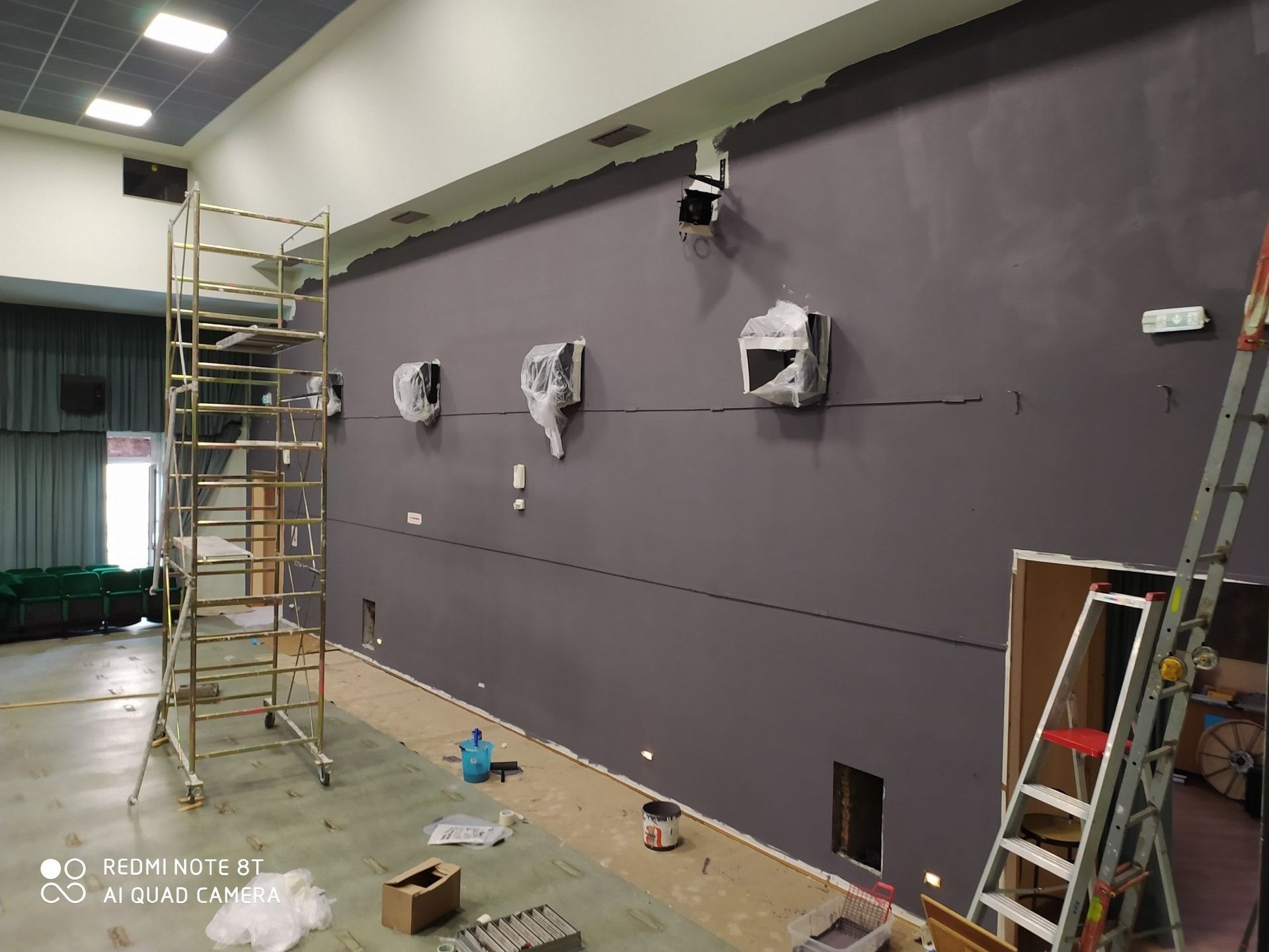 Si sta dipingendo una grande parete in una stanza con un'impalcatura e una scala.