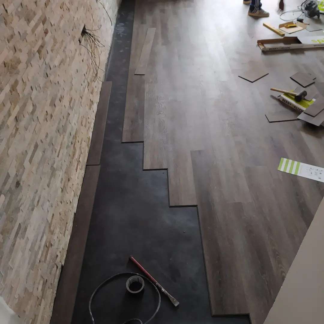 Un pavimento in legno viene installato in una stanza con un muro in mattoni