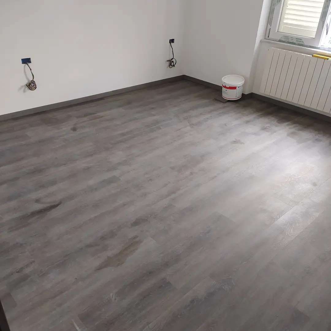 Una stanza con un pavimento in legno e un secchio sul pavimento.