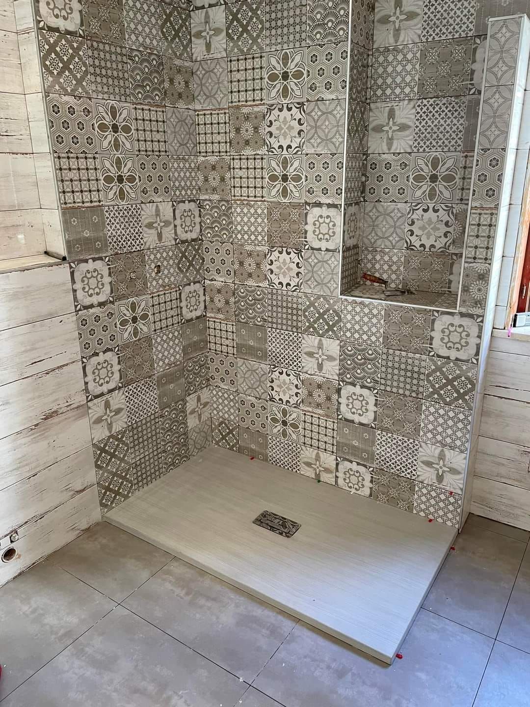 Un bagno con cabina doccia e pareti piastrellate.