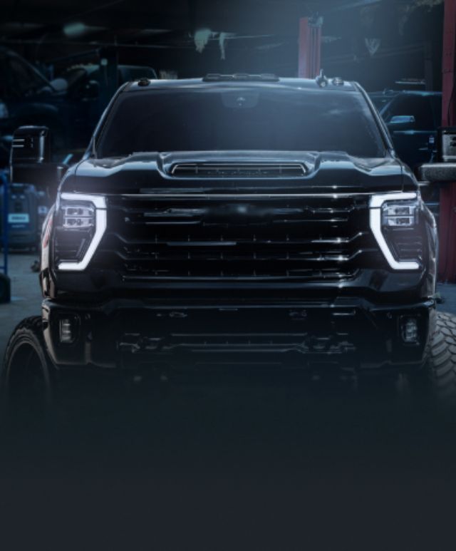 Black truck with bright headlights parked in a garage. | Bad Habit Motorsports LLC