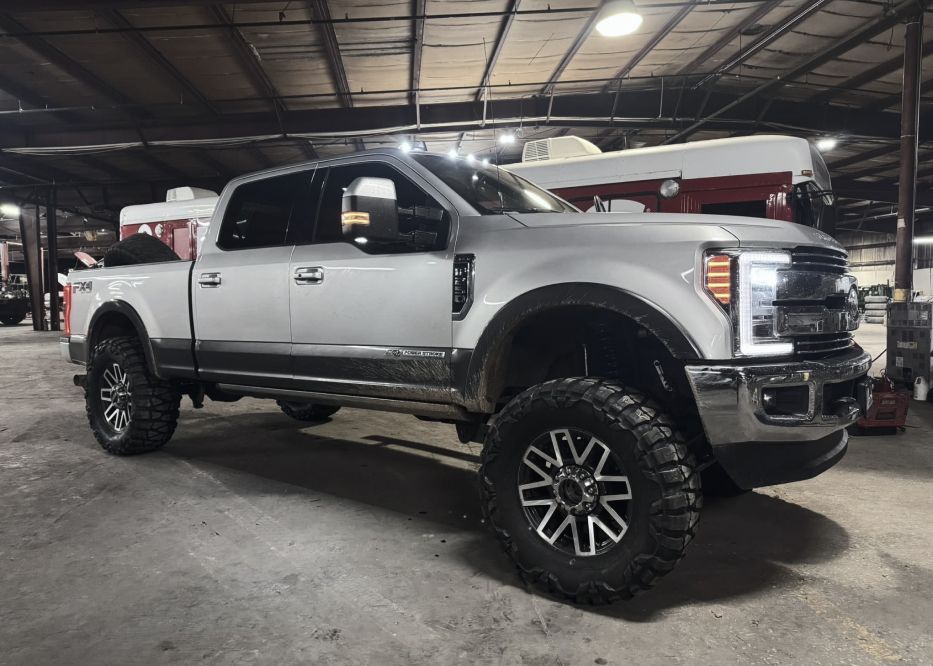 Silver pickup truck with black tires and rims parked inside a warehouse. | Bad Habit Motorsports LLC