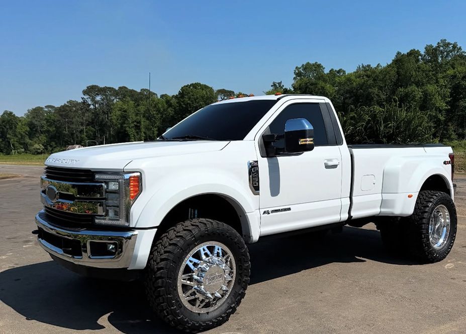 White Ford dually pickup truck with large tires, parked outdoors on a sunny day. | Bad Habit Motorsports LLC