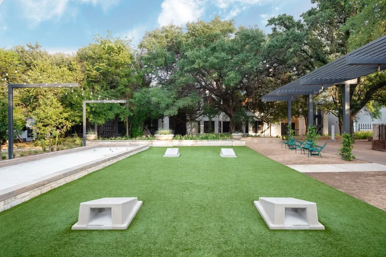 Outdoor bocce ball court and cornhole game area with lounge seating.