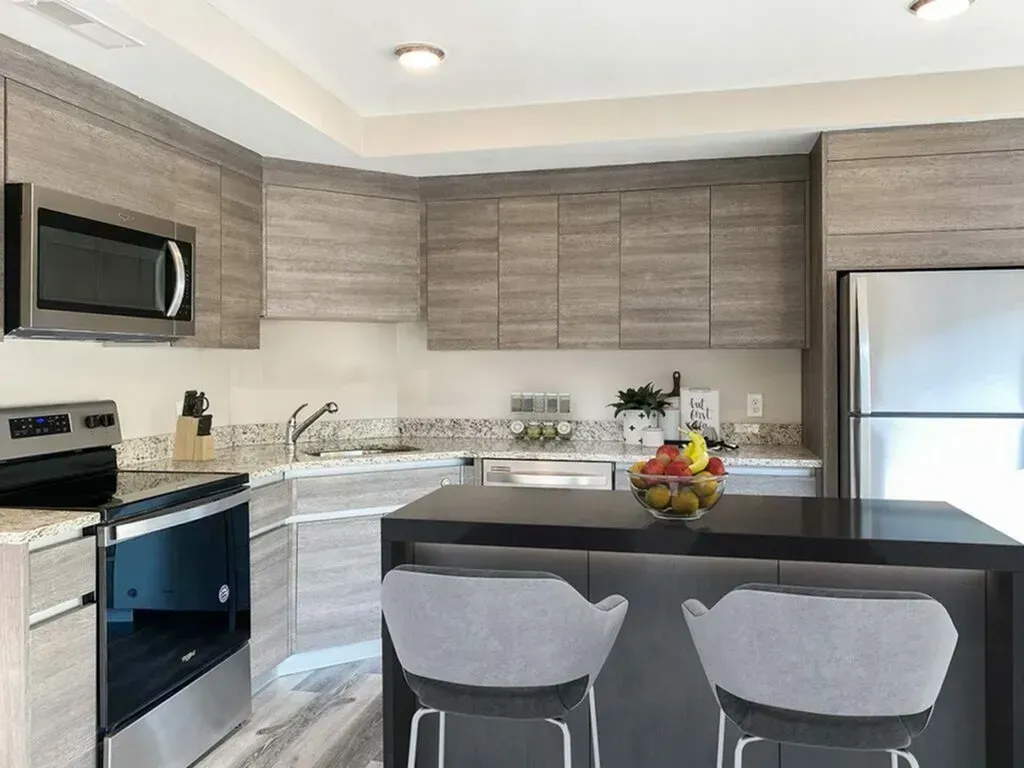 Modern kitchen with gray cabinets, stainless steel appliances, and a black island with two bar stools.
