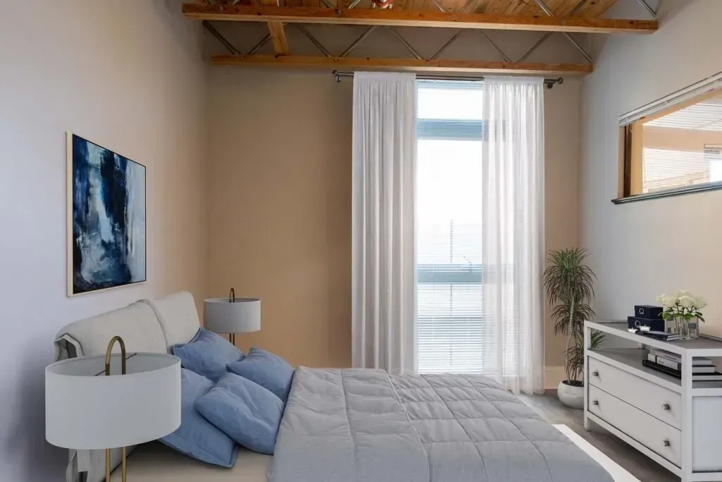 Bedroom with bed, blue pillows, white dresser, window with sheer curtains, and art.