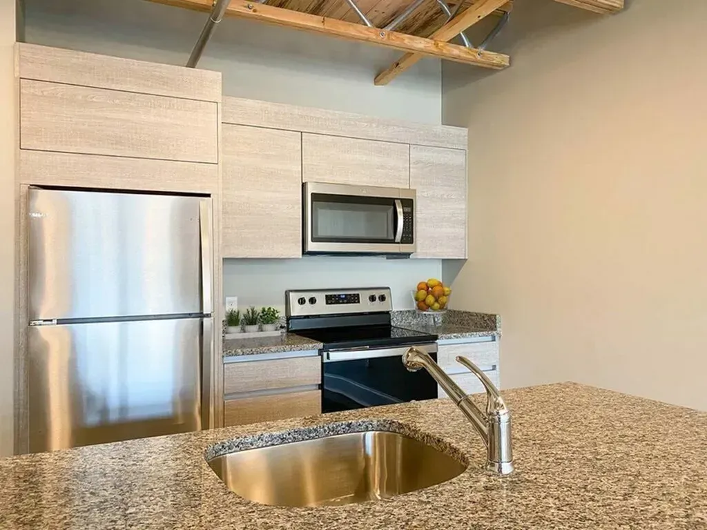 Modern kitchen with stainless steel appliances, light wood cabinets, and granite countertops.