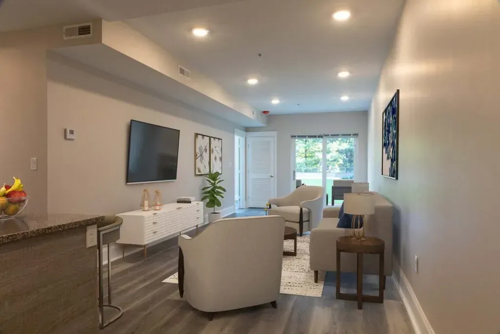Bright living room with gray flooring, furniture, TV, and access to an outdoor area.