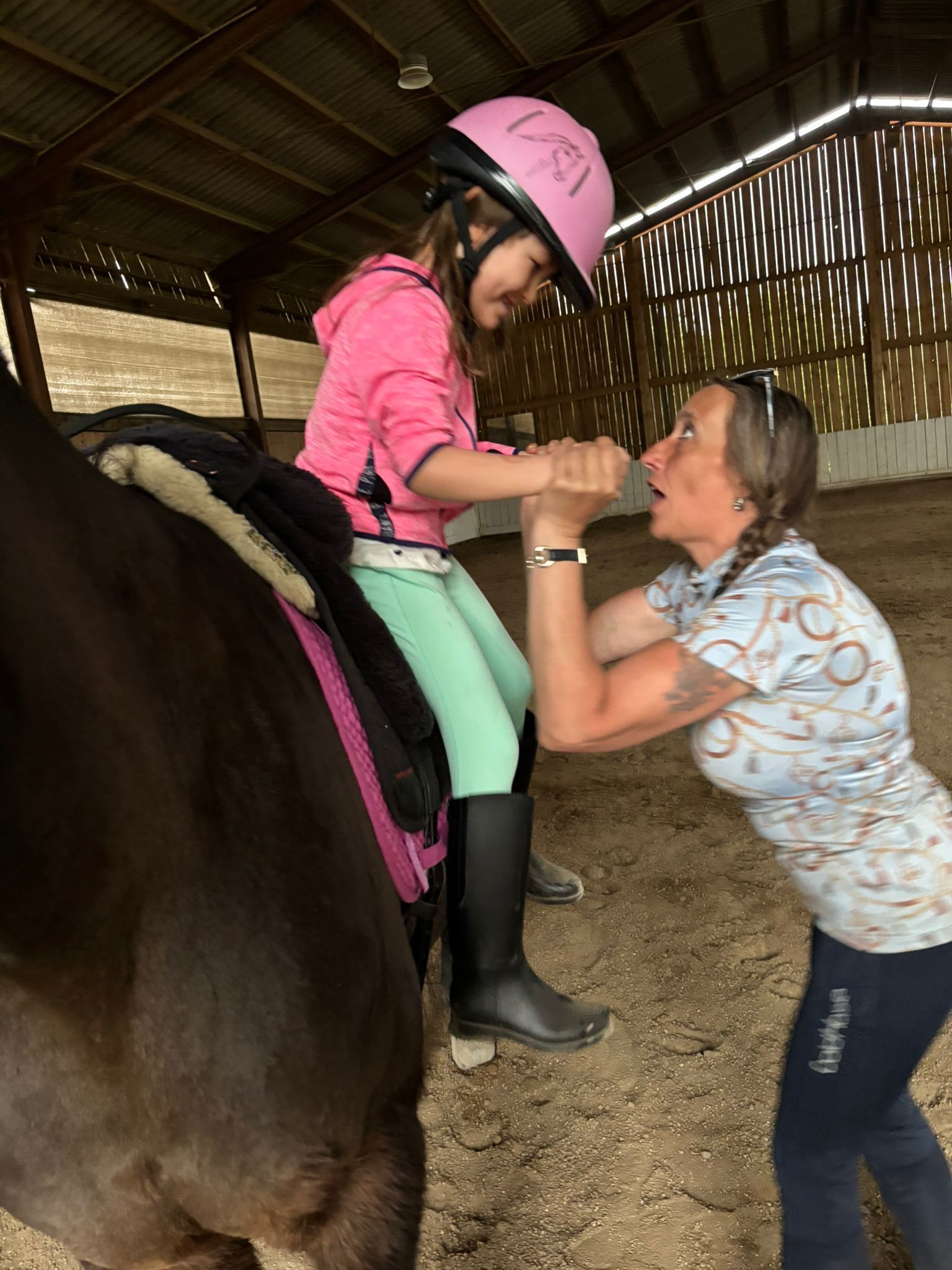 Ein Kind auf einem Pferd auf einem Reiterhof mit einer Frau