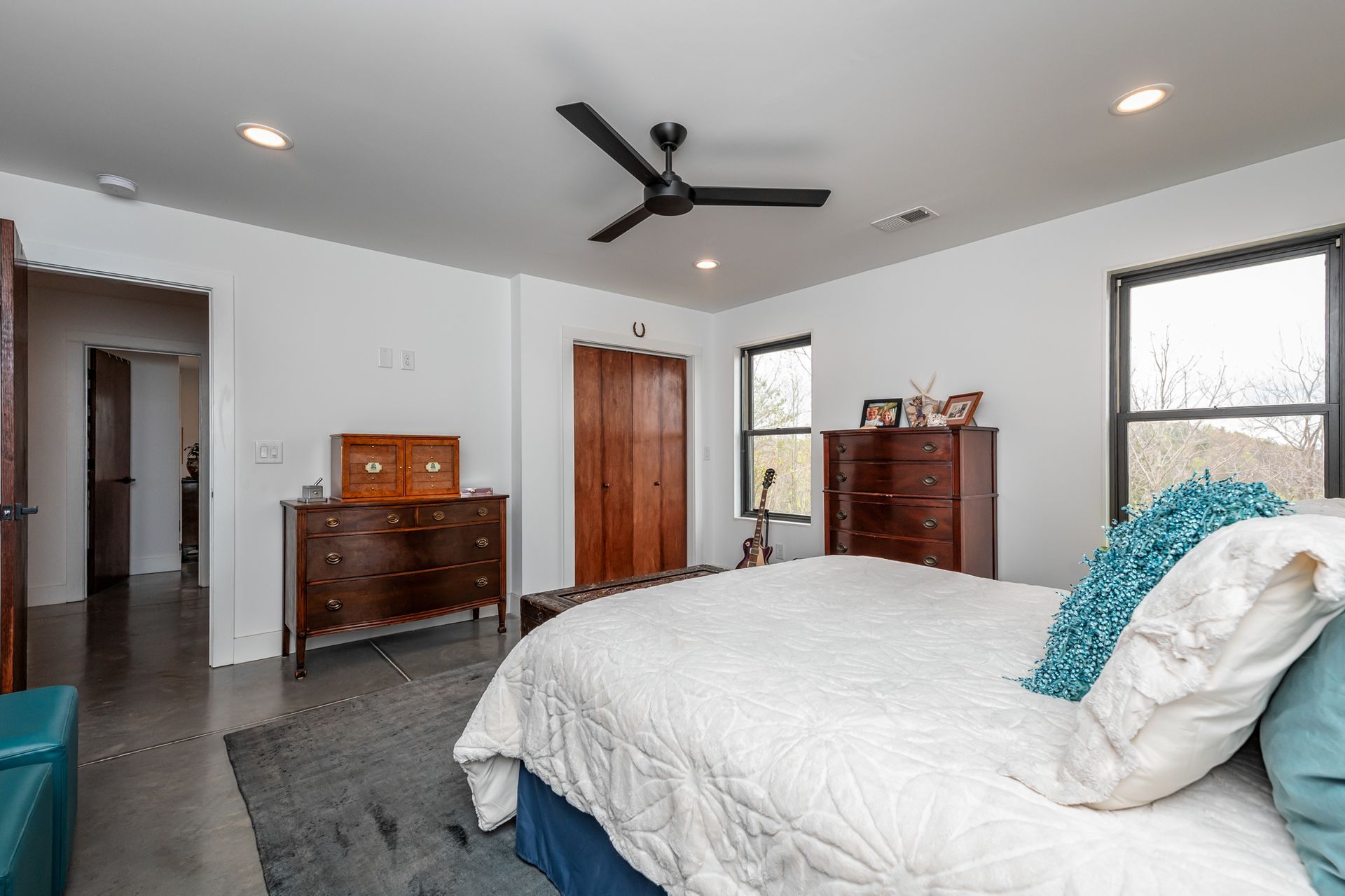 A bedroom with a bed , dresser , and ceiling fan.