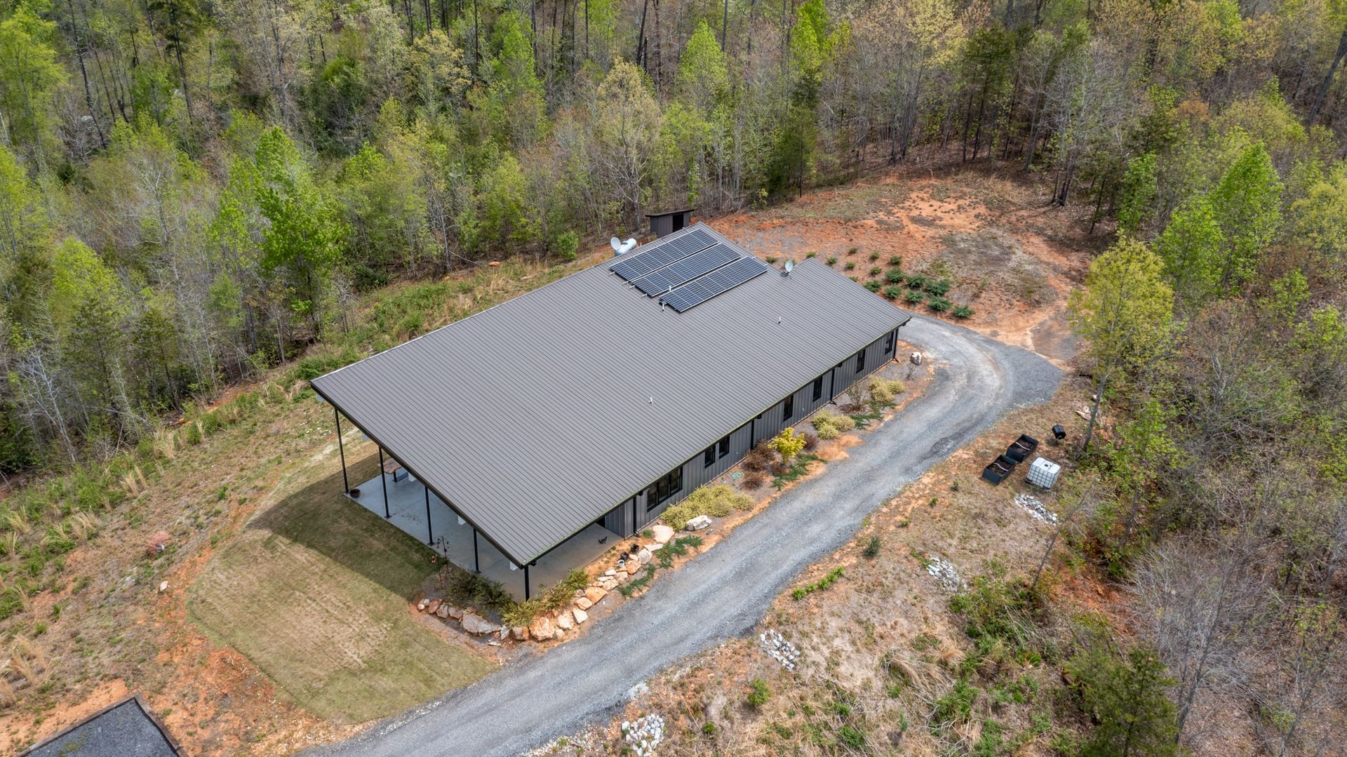 An aerial view of a house in the middle of a forest.