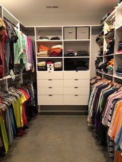 A walk in closet filled with lots of clothes and drawers.