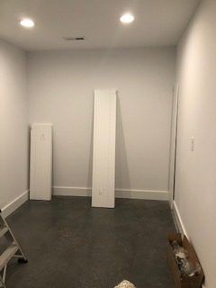 An empty room with a ladder and a box on the floor.