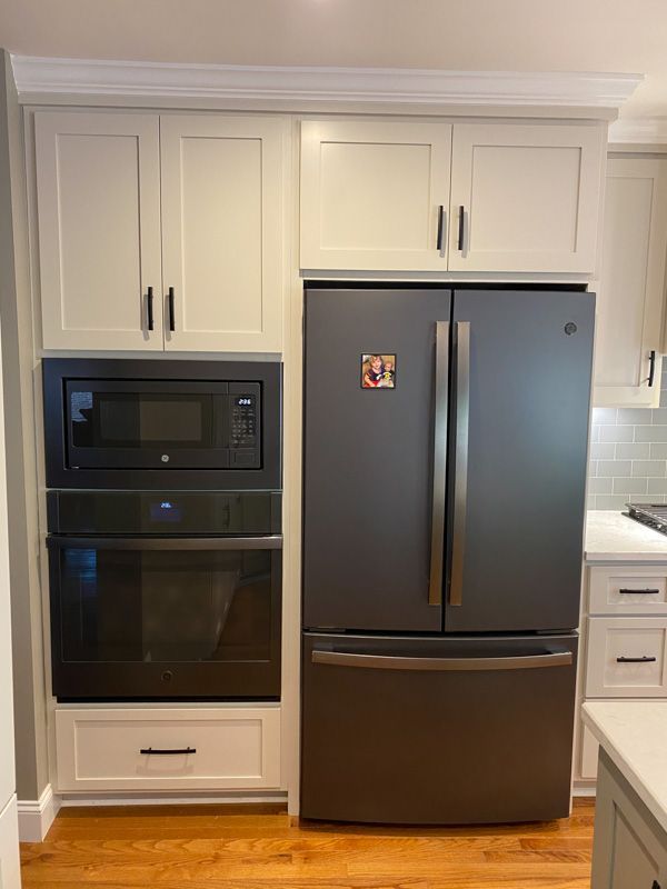 A kitchen with a refrigerator , oven and microwave.