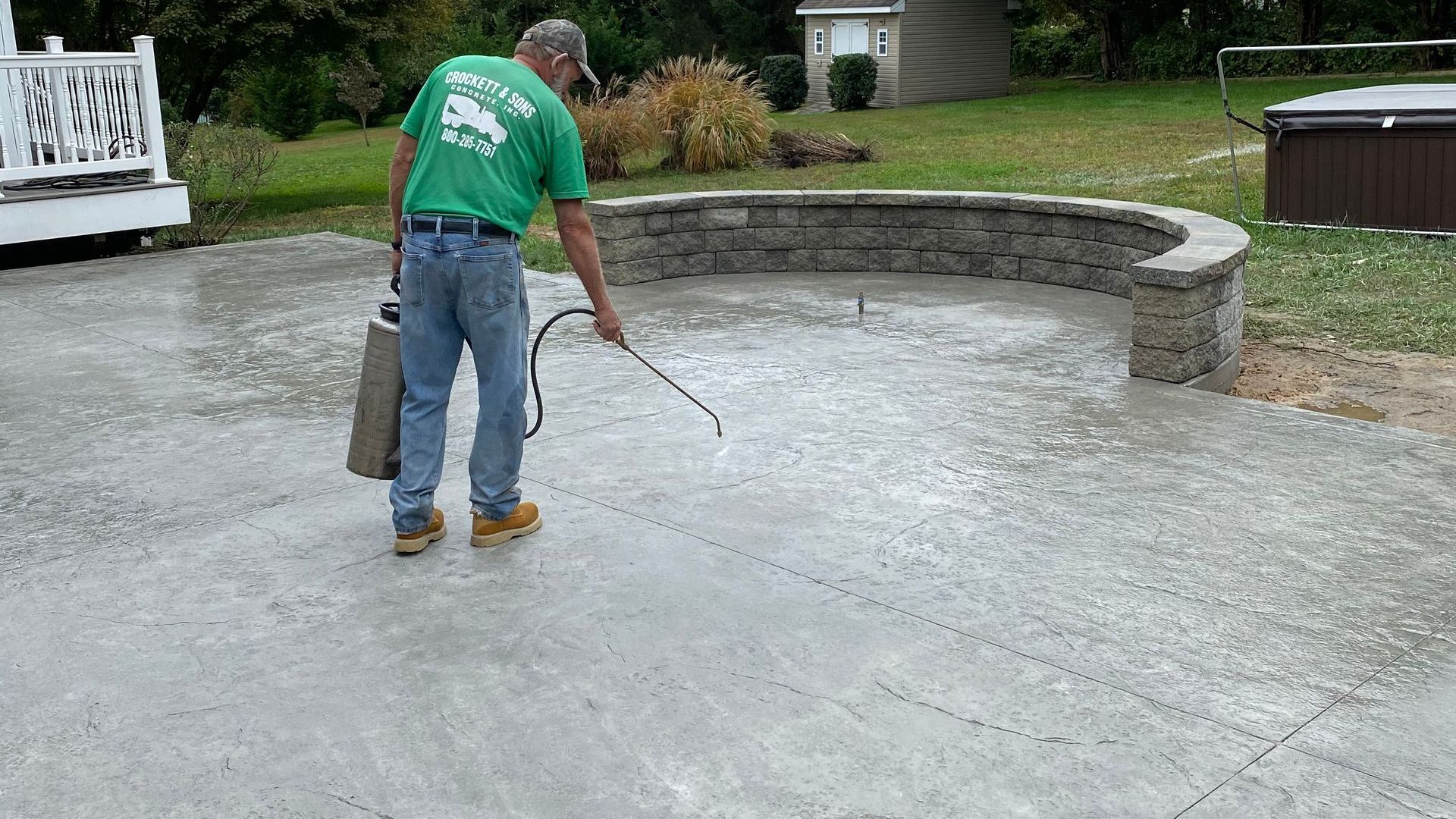 worker spraying concrete sealer on concrete patio in crockett and sons concrete uniform
