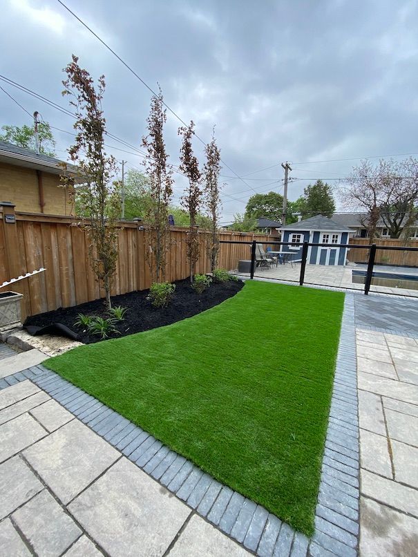 A backyard with a wooden fence and a lush green lawn.