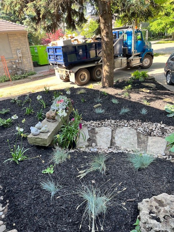 A dump truck is parked in a garden next to a tree.
