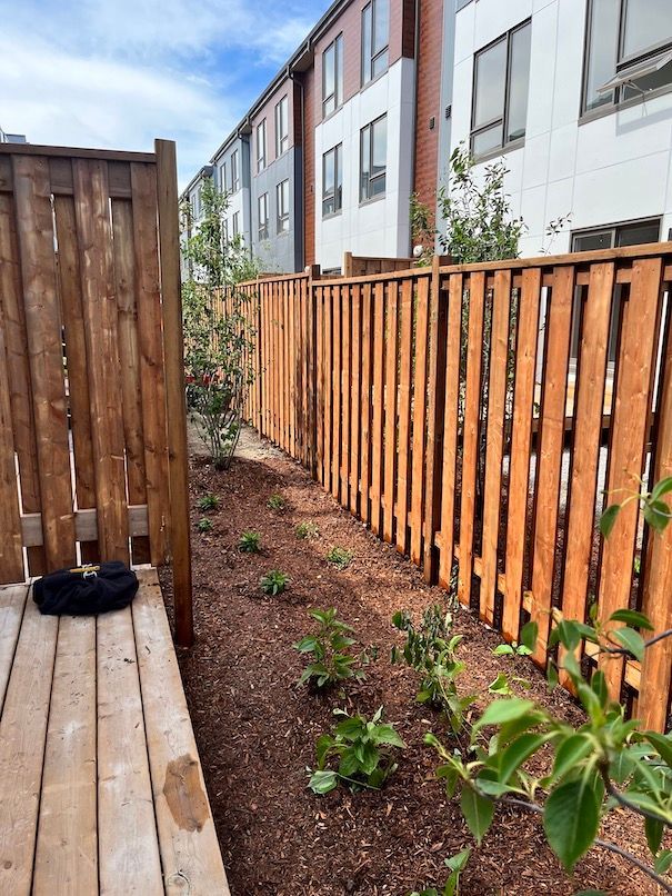A wooden fence surrounds a garden in front of a building.