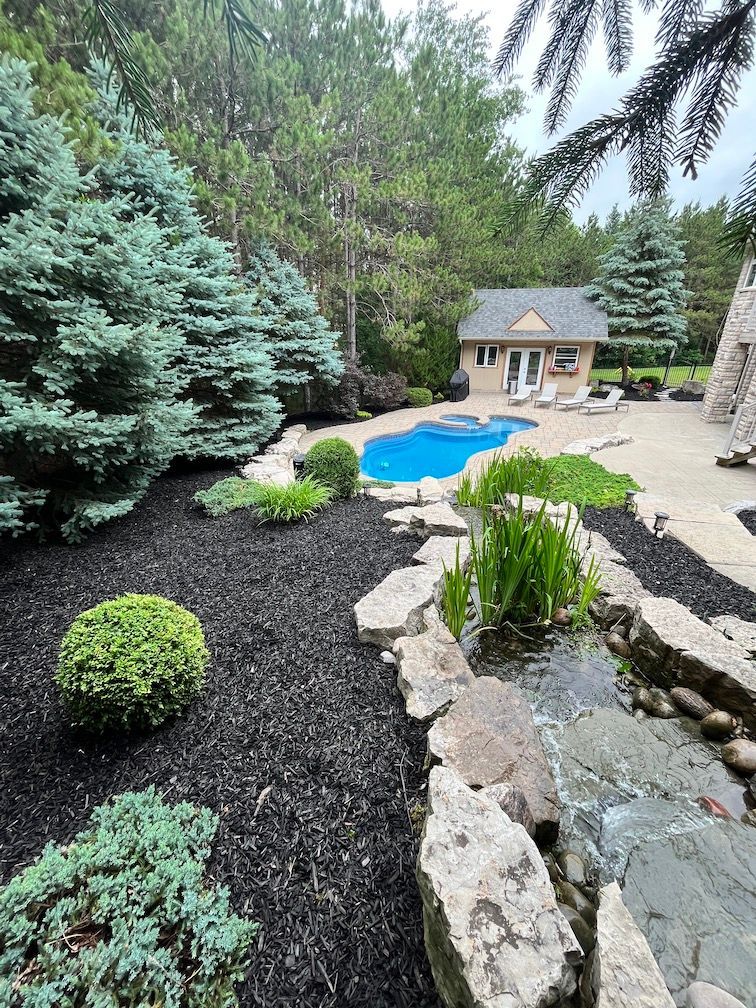 There is a large pool in the backyard of a house surrounded by trees.