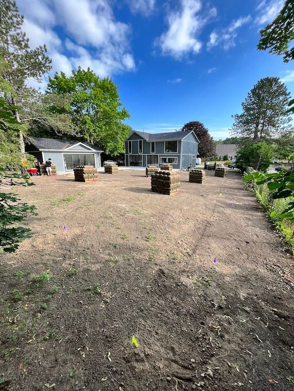 A large house with a lot of hay bales in front of it.