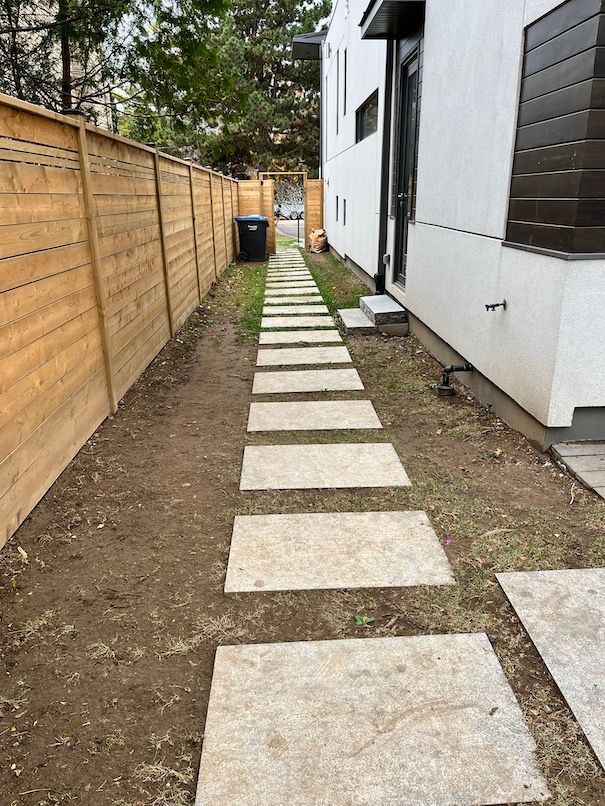 A walkway leading to a house with a wooden fence.