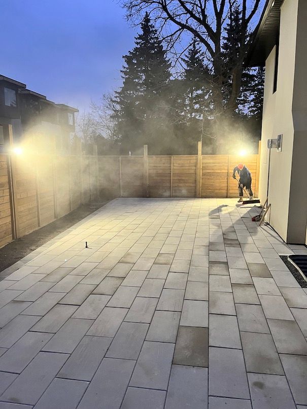 A man is working on a patio in front of a house at night.