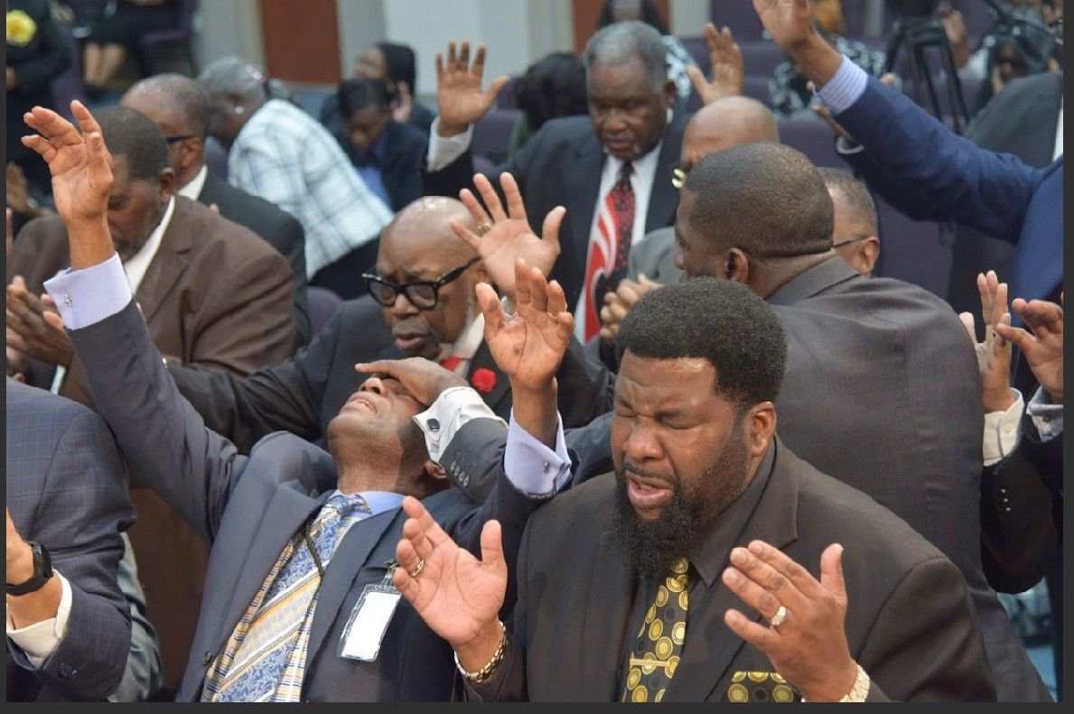 A group of men are raising their hands in the air