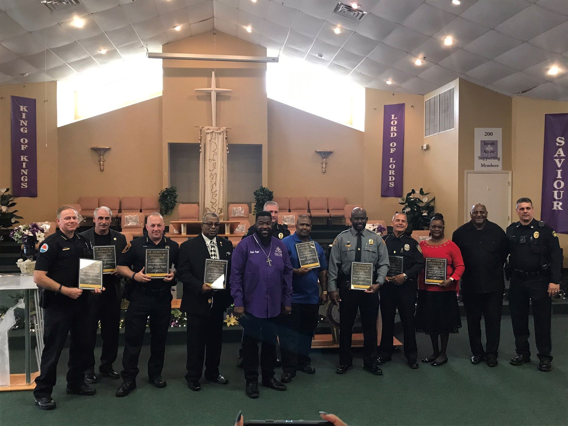A group of police officers are standing in a church holding awards.