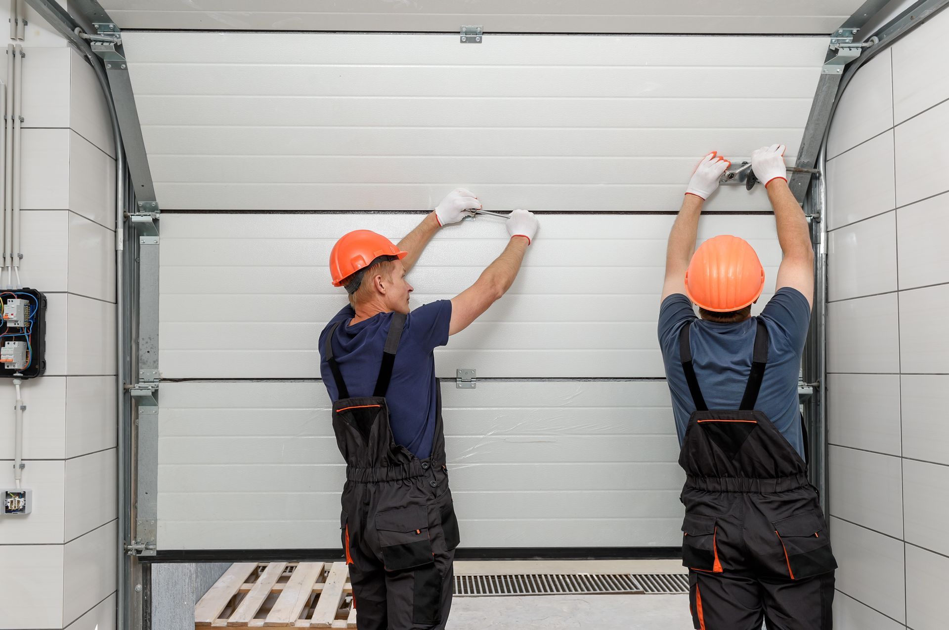 Men working on garage gate repairs with tools and equipment