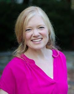 A woman in a pink shirt is smiling for the camera.