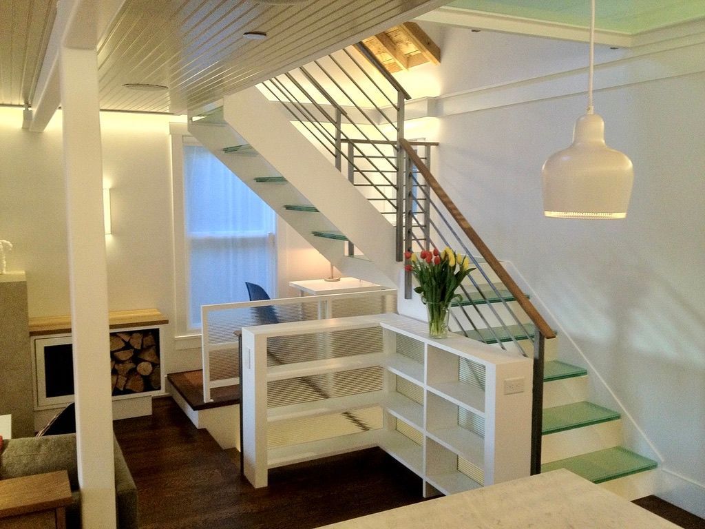 Interior with a staircase, bookshelves, and a fireplace. White and wooden accents with a vase of flowers.