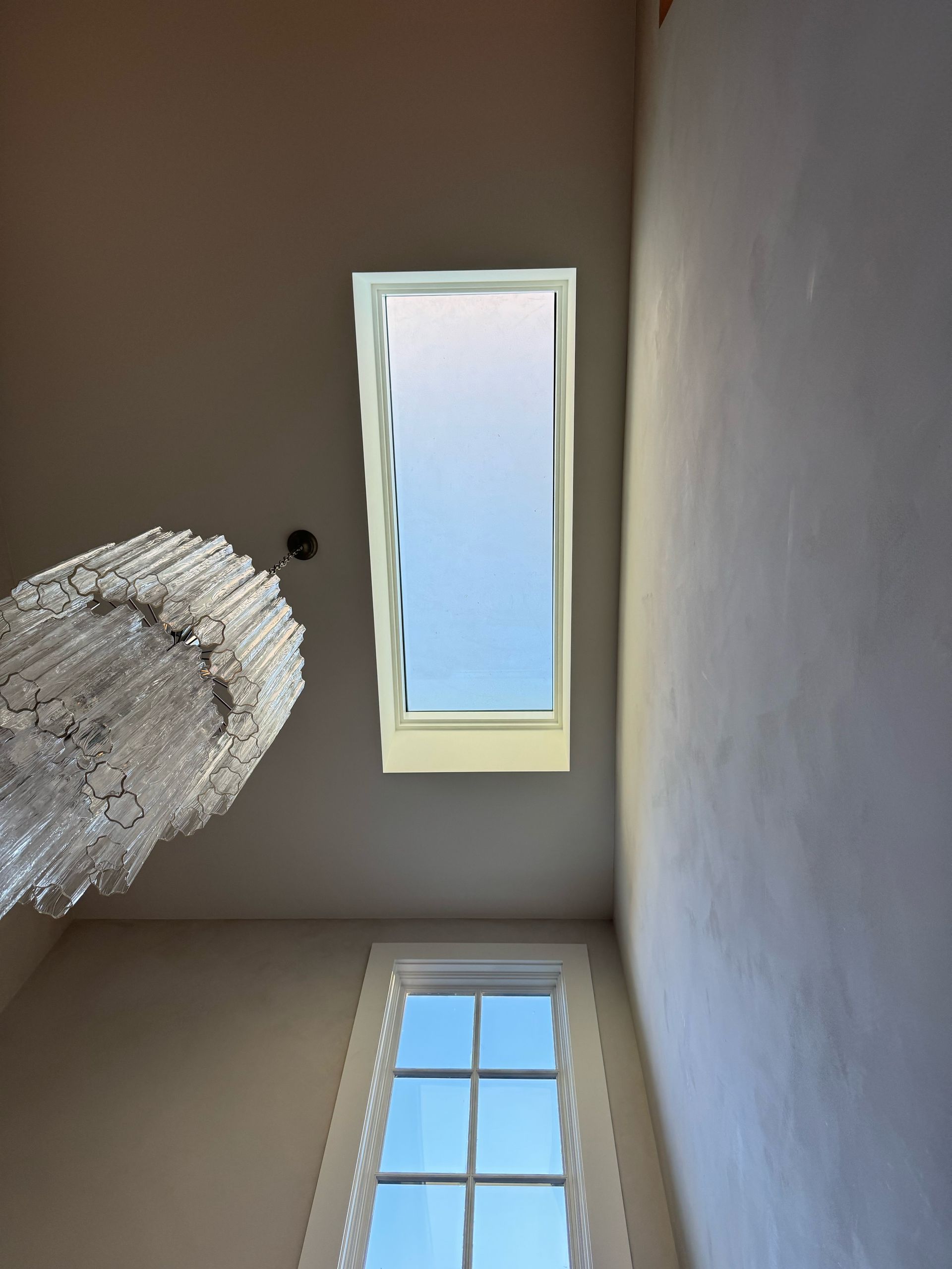 walkable Skylight and window in a room with chandelier; blue sky visible.