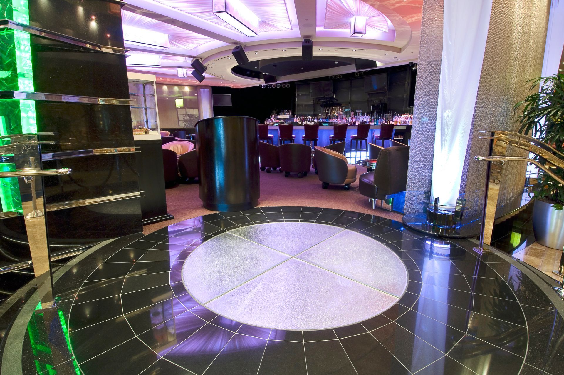 Circular dance glass floor in a dimly lit venue with tables and chairs in the background.