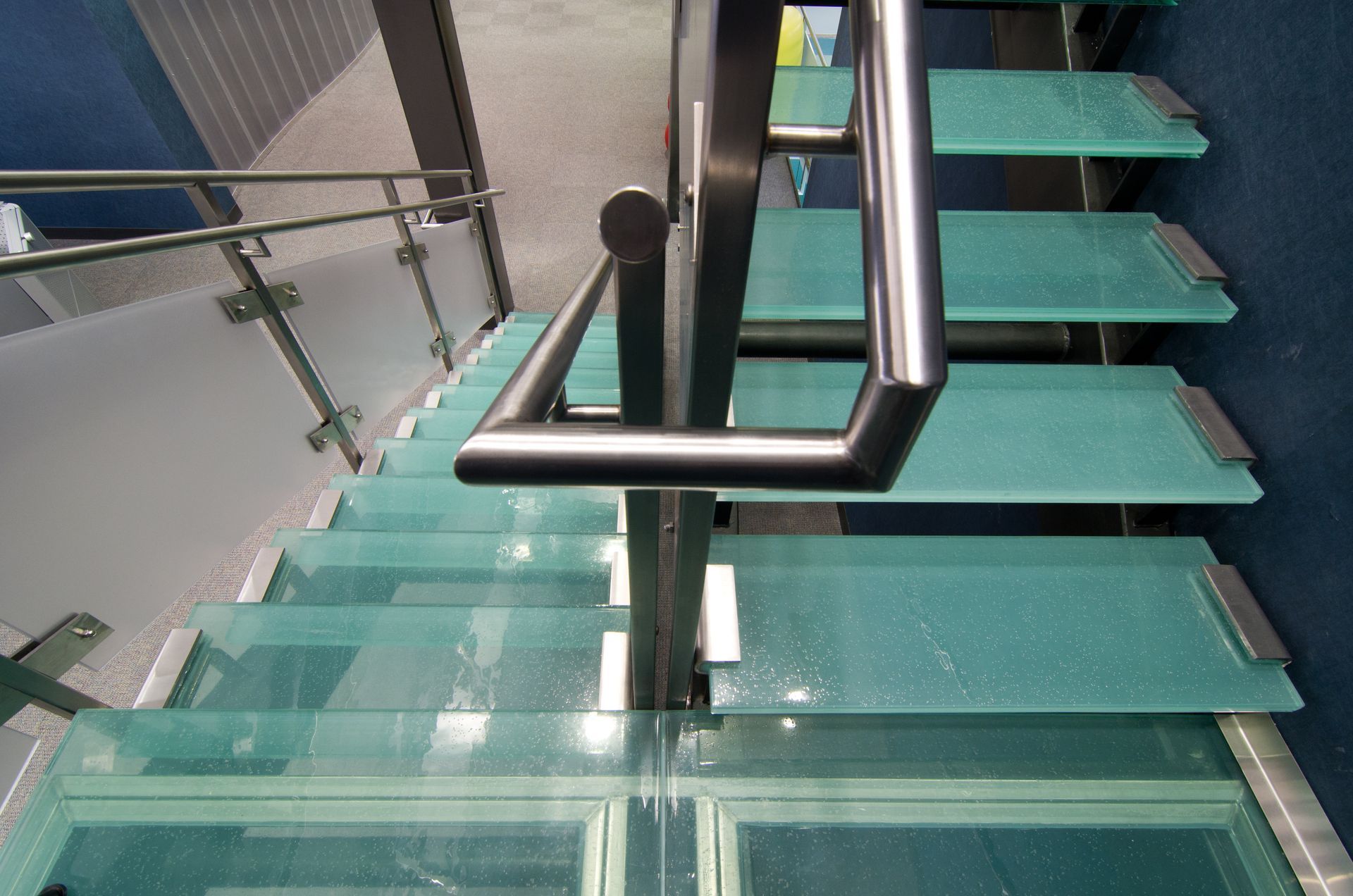 Glass staircase with metal handrails, descending from above.
