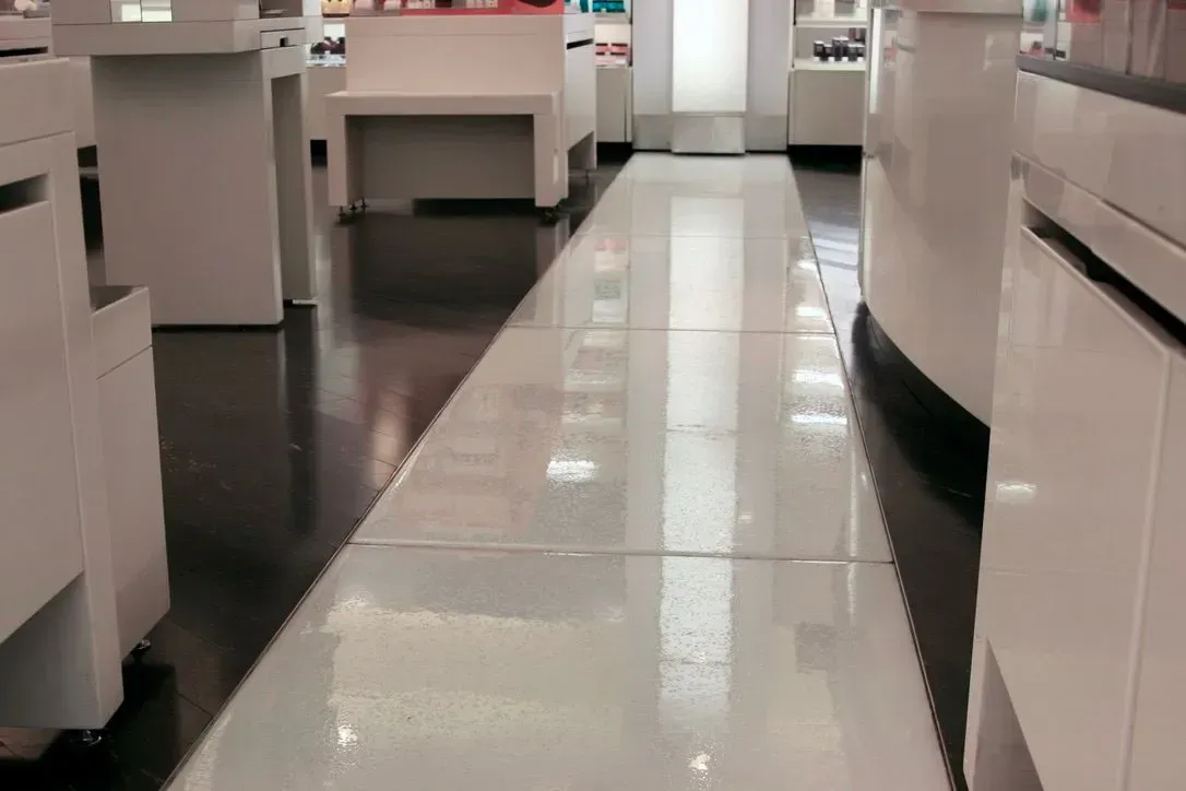 White and black tile and glass floor in a retail store with white display counters.