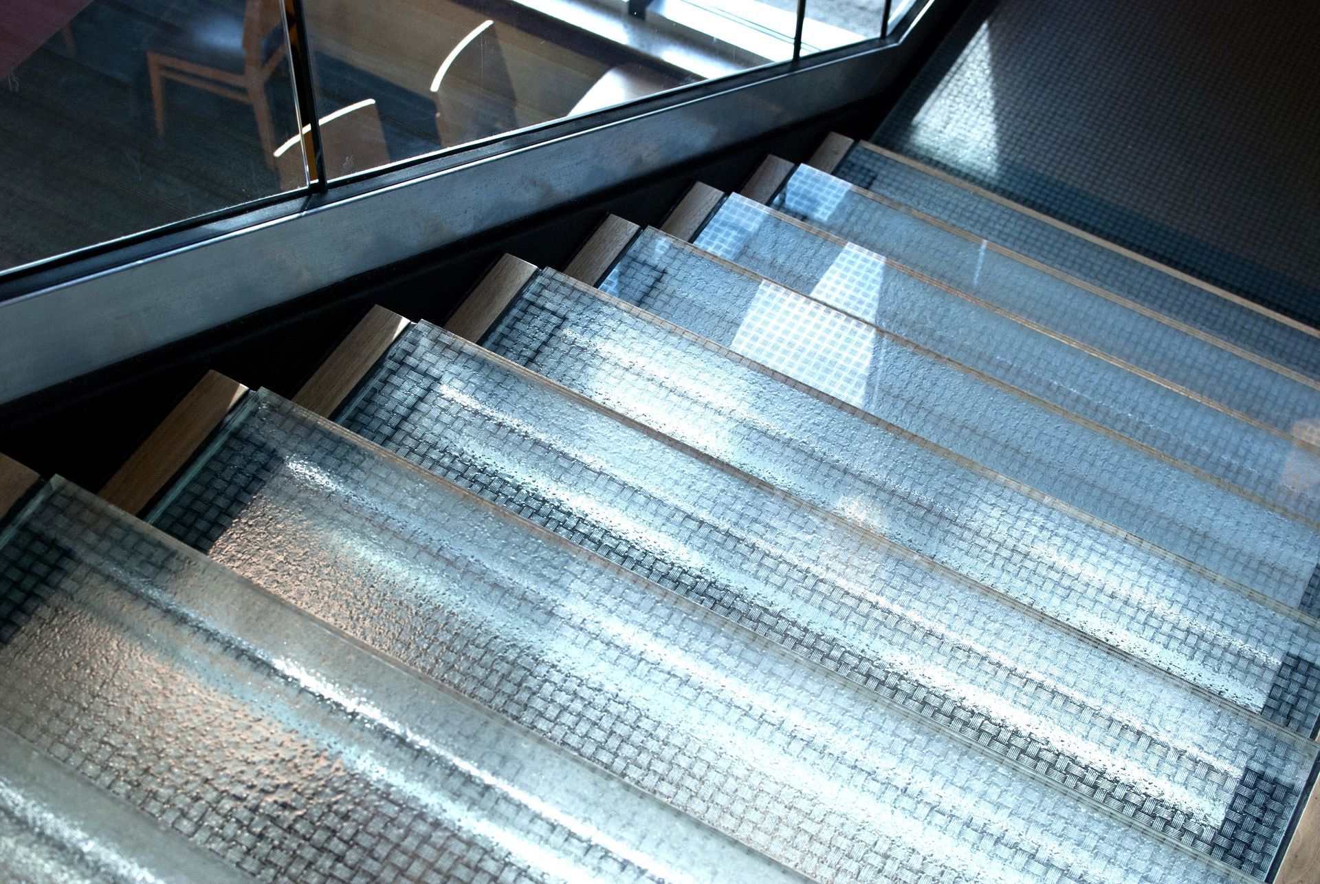 Glass staircase from high angle, bright light, textured surface.