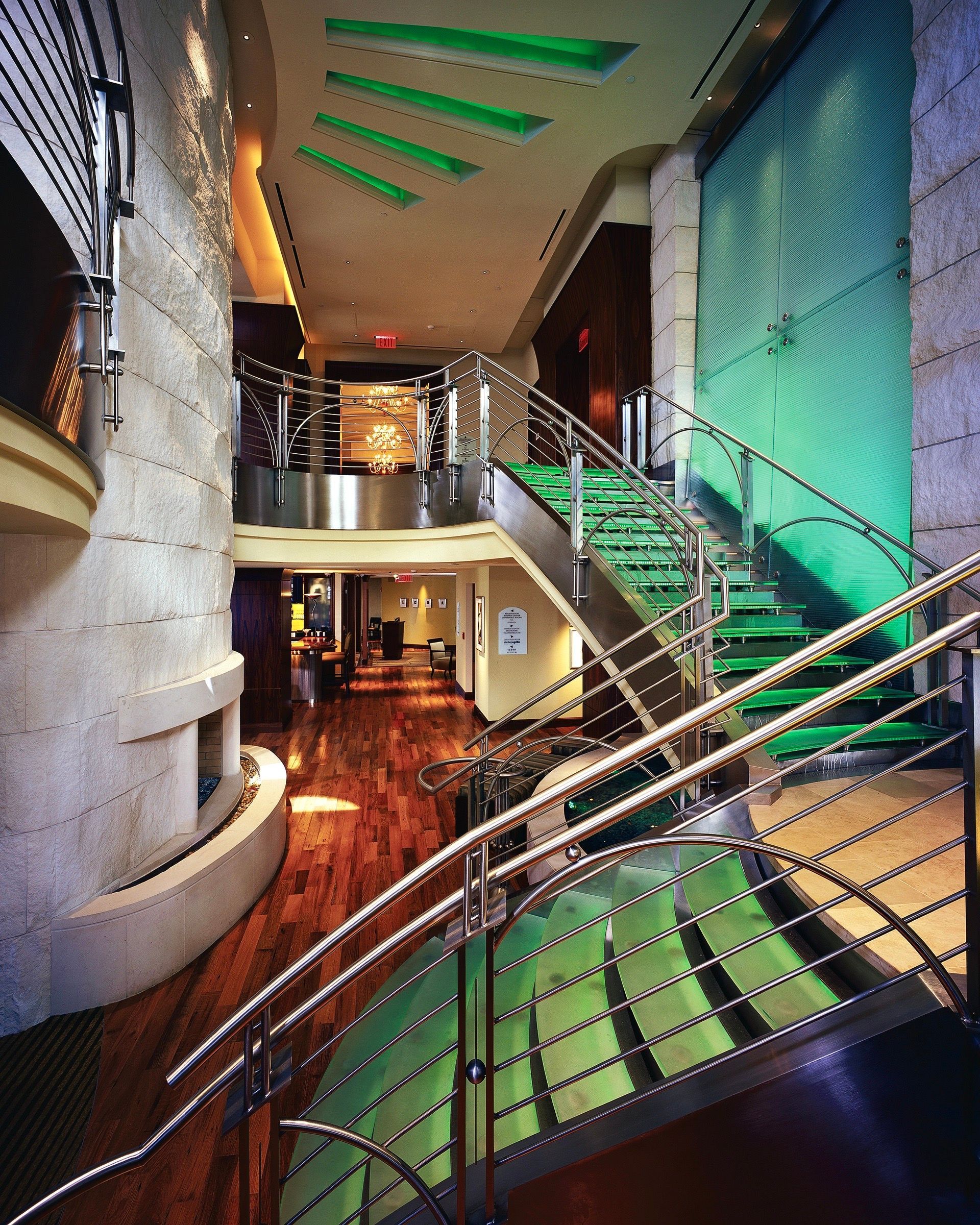 A modern interior with a staircase, green accents, and a wooden floor.