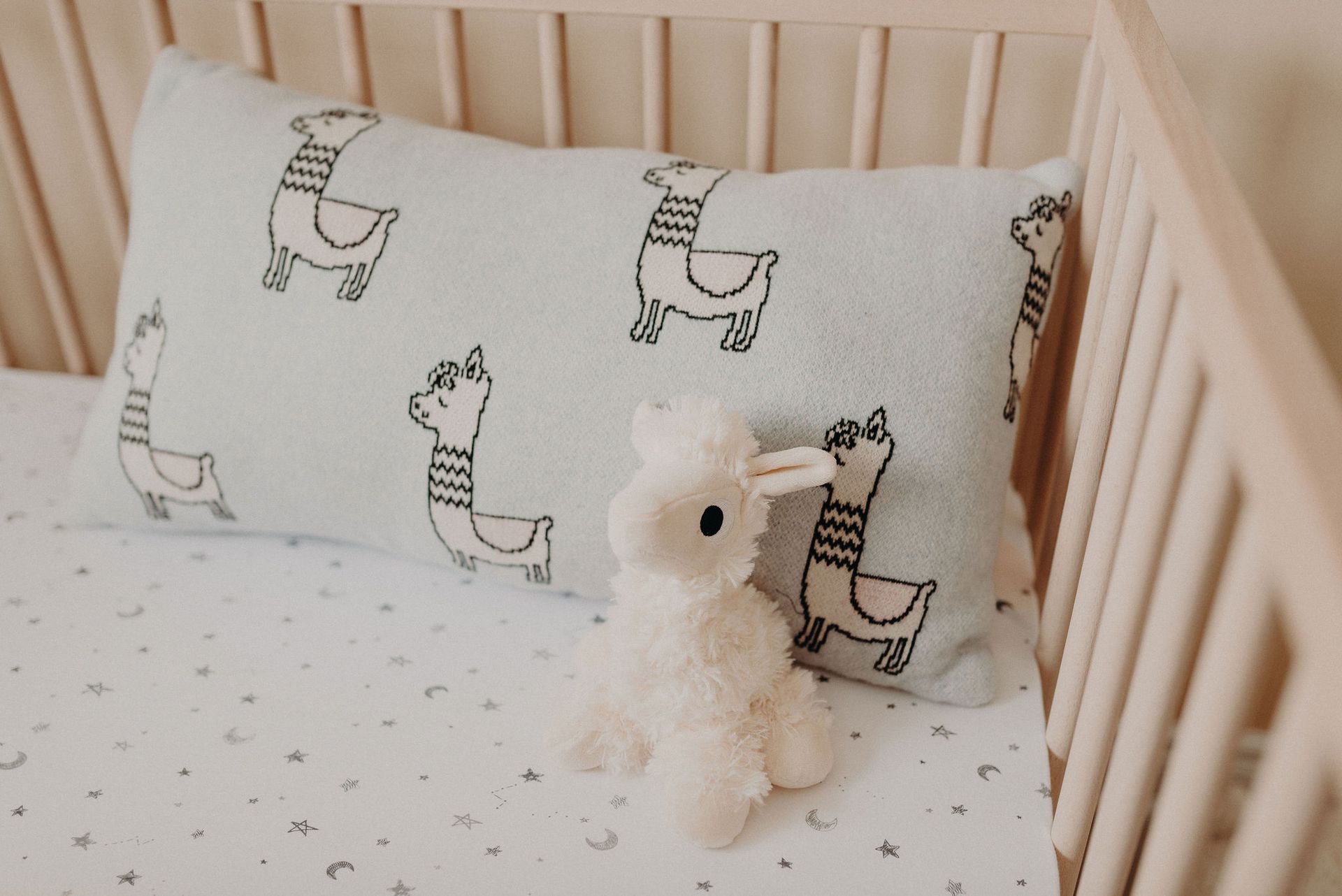 stuffed Llama toy  in a crib with a pillow