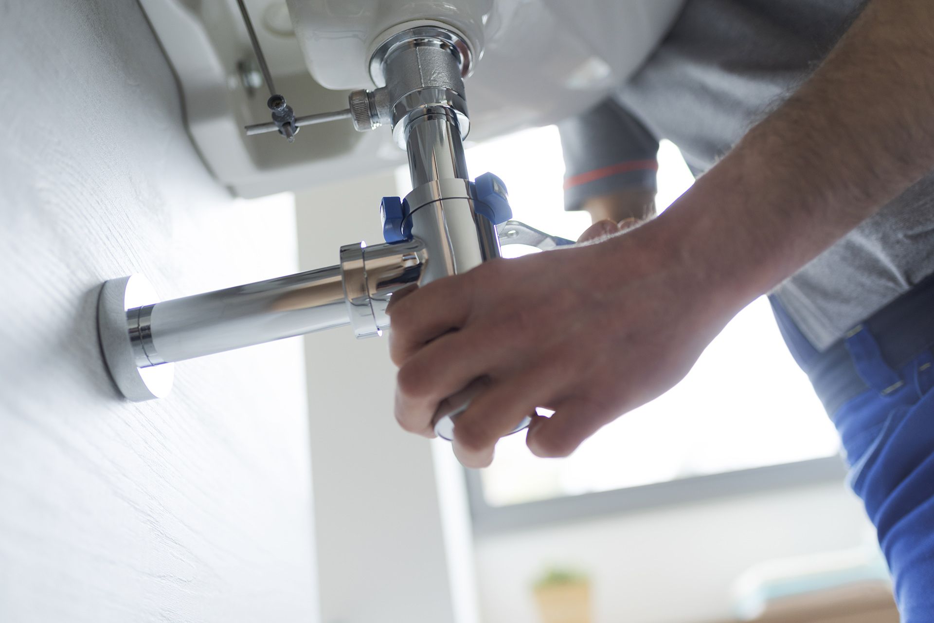 A Man Is Fixing A Sink Pipe With A Wrench