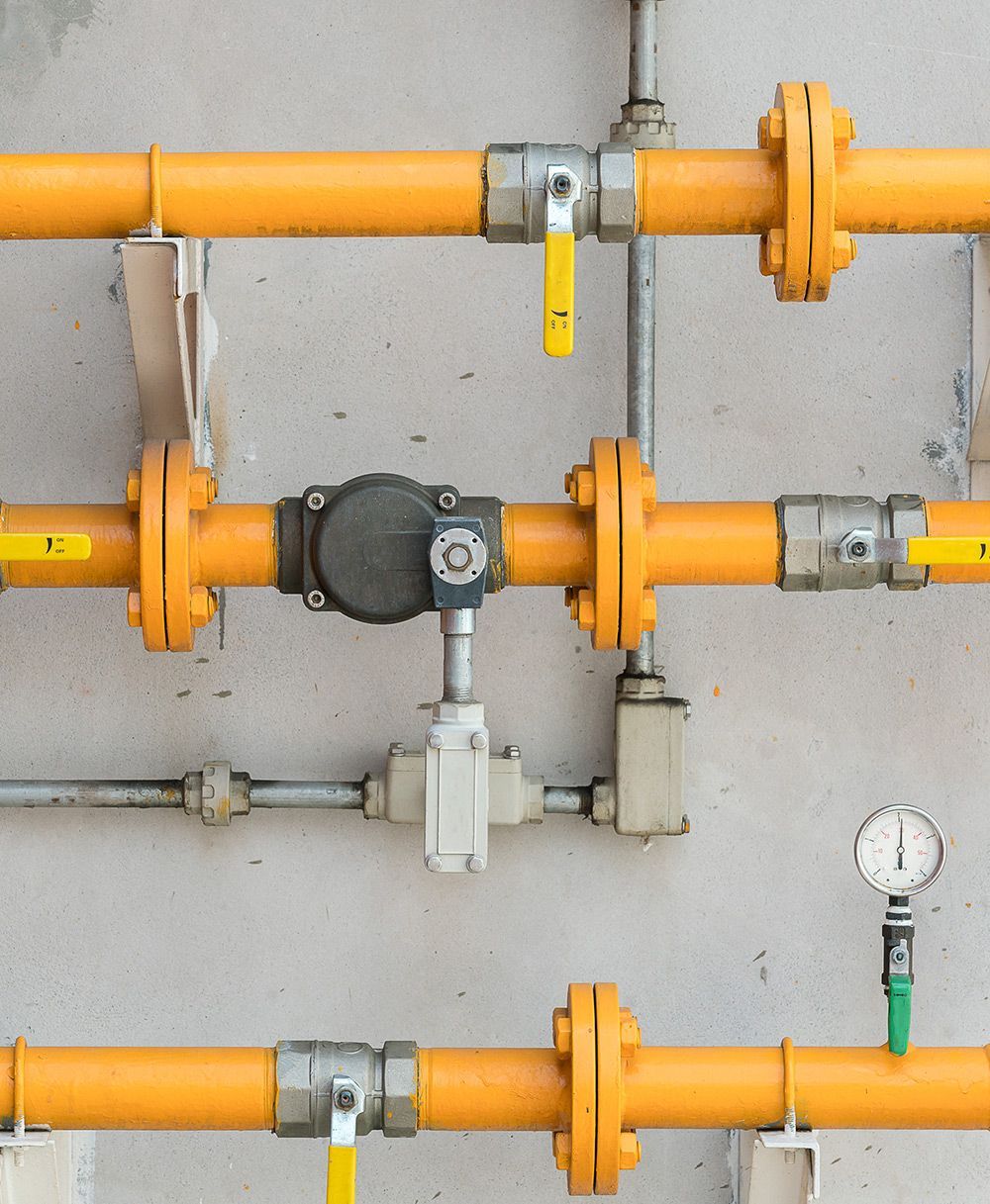 A Bunch Of Yellow Pipes And Valves On A Wall