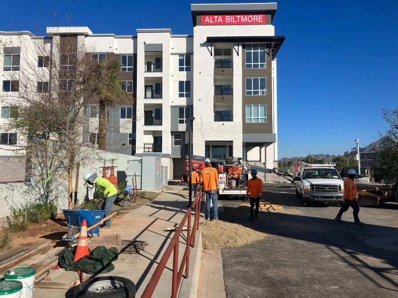A Group Of Construction Workers Are Working In Front Of A Building That Says Alta Baltimore
