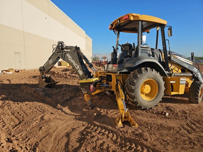 A Yellow Tractor Is Parked In The Dirt In Front Of A Building